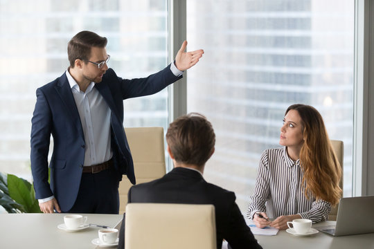 Mad male worker gesturing asking female colleague leave business meeting, angry businessman standing showing to doors having dispute with woman partner, associates argue at negotiations