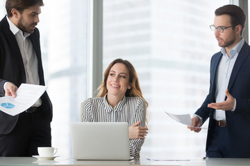 Happy millennial businesswoman lost in thought at workplace avoiding mad or annoying colleagues asking questions, smiling female boss or woman ceo dreaming in office abstracted from work