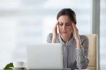 Exhausted businesswoman massaging temples suffering from headache at workplace, tired female CEO...