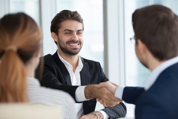 Close up view of HR managers handshake smiling male job candidate congratulating with hiring, happy satisfied employee shake hand employers greeting him, thanking for good interview, welcoming at work