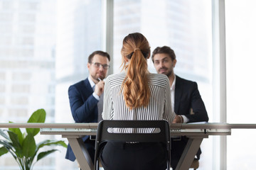Back view of woman candidate interview with male HR managers in modern office, thoughtful...