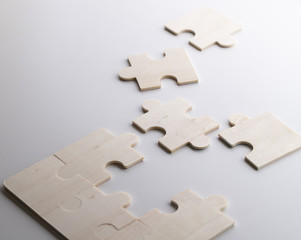 Fototapeta premium Incomplete puzzles lay on wooden white table