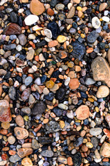 small stones on the beach covered by white wave foam