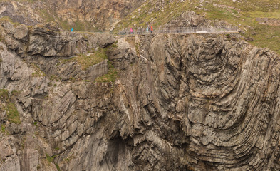 cliff face of patterned rock formation with people on top as background