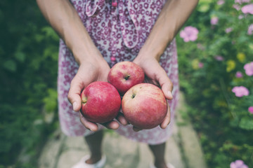 A woman is holding apples.