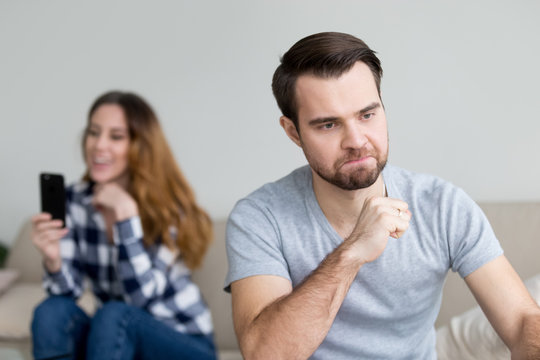 Angry husband feel jealous of happy wife texting on phone to somebody, mad man furious about beloved woman having fun, suspect spouse in cheating, thinking about divorce. Relationships problem concept
