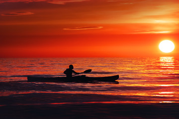 Silhouette of a man and canoe at a colorful summer ocean sunset: paddling is a perfect activity at the beach. L&oslash;nstrup in North Jutland in Denmark, Skagerrak, North Sea