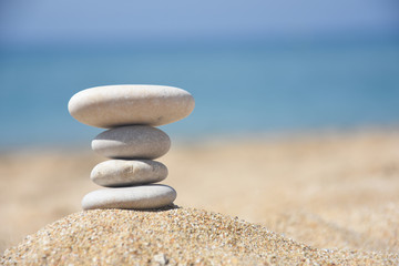 Fototapeta na wymiar Balanced stone pyramid on sand on beach. Zen rock, concept of balance and harmony
