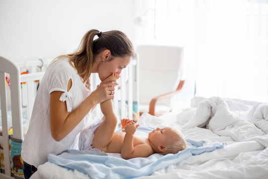 Young mom, changing baby diaper after bath