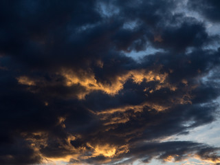 Fototapeta na wymiar Blau schwarze Wolken mit orangenen Rändern