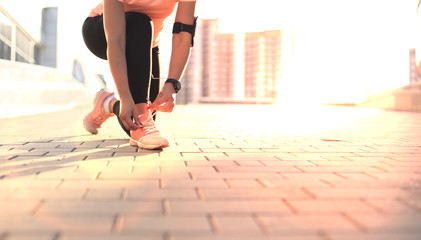 Young fitness attractive sporty girl runner ties up the shoelaces on her sports shoes getting ready...