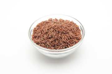 Arroz rojo integral en un bol de cristal sobre fondo blanco