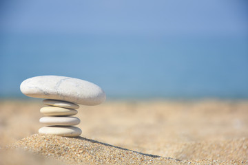 Balanced stone pyramid on sand on beach. Zen rock, concept of balance and harmony