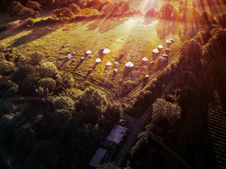 Aerial view of idyllic campsite at sunset with North London countryside as the backdrop. Bell tents...
