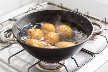 Potatoes boiling in a saucepan on a gas hob
