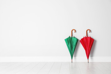 Beautiful bright umbrellas on floor near white wall with space for design