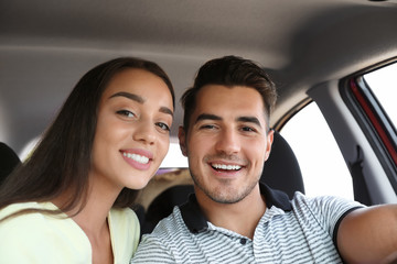 Happy young couple in car on road trip