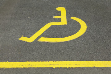 PAINTED ICON OF YELLOW WHEEL CHAIR IN DISABLED PARKING BAY