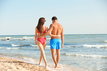 Happy young couple walking together on beach