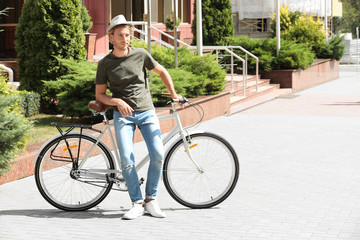 Naklejka premium Handsome young man with bicycle on city street