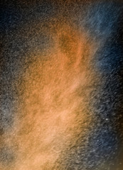 ABSTRACT IMAGE OF ORANGE AND BLUE PARTICLES SWIRLING IN TURBULENT AIR