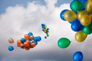 bundles of balls of blue, yellow, red and green in a bright cloudy sky