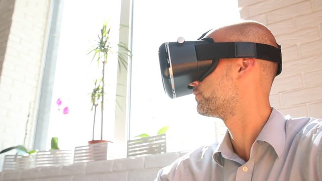 Man using virtual reality headset at office. Bearded man uses VR headset display for game