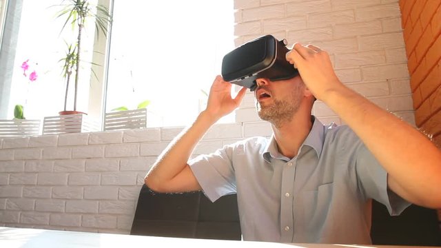 Man using virtual reality headset at office. Bearded man uses VR headset display for game