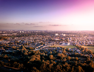 Sunrise aerial view of London City Skyline and famous skyscrapers in the the background above a London housing estate. Taken near the M25, fields and community housing can be seen in the foreground