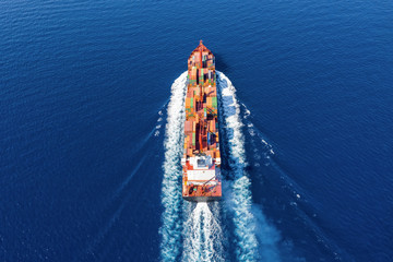 Luftaufnahme eines beladenen Containerschiffes in voller Fahrt über blauem Meer