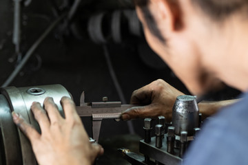 Men's hands with a Vernier caliper measuring the size of the details at work piece on Lathe...