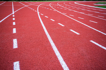 red rubber running racetrack with white lines in outdoor stadium