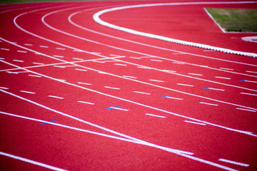 red rubber running racetrack with white lines in outdoor stadium