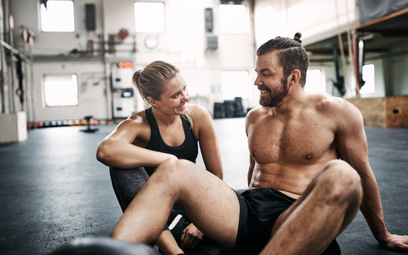 Fit couple smiling and talking during a break from exercising