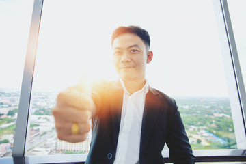 portrait of smiling chinese businessman  show thumb up on the top of building