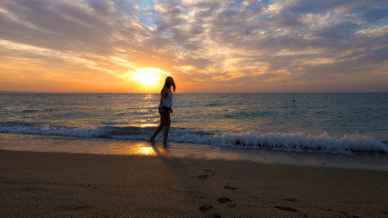 Fototapeta na wymiar Woman relaxing at the sea admiring the sunset. Relaxing summer vibe