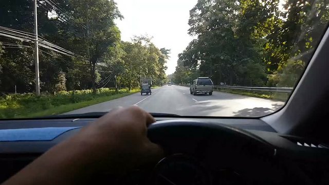 hand of asian man driving a car on highway in Thailand