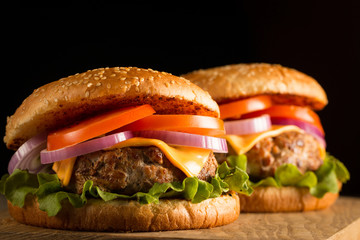 Home made hamburger with beef, onion, tomato, lettuce and cheese. Fresh burger close up on wooden rustic table with potato fries, beer and chips. Cheeseburger.