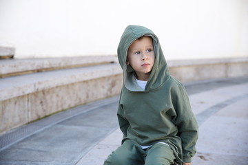 cute kid or child in the hoodie sitting on a ball in the park 