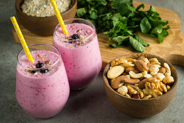 Glasses of berry smoothie with nuts, mint, blueberry, blackberry, raspberry, and yogurt on wooden table. Weight loss and diet concept. 