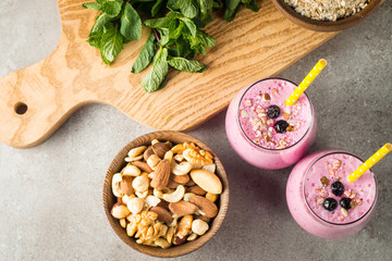 Glasses of berry smoothie with nuts, mint, blueberry, blackberry, raspberry, and yogurt on wooden table. Weight loss and diet concept. 