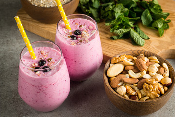 Glasses of berry smoothie with nuts, mint, blueberry, blackberry, raspberry, and yogurt on wooden table. Weight loss and diet concept. 