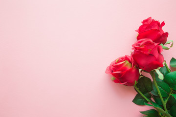 Beautiful, artificial red roses on pastel pink table. Minimalism. Mockup for different positive ideas. Empty place for sentimental, emotional text, lovely quote or sayings. Top view. Flat lay.