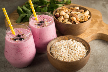 Glasses of berry smoothie with nuts, mint, blueberry, blackberry, raspberry, and yogurt on wooden table. Weight loss and diet concept. 