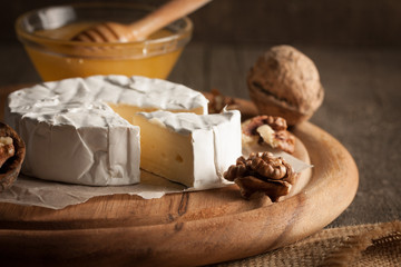 Camembert and brie cheese on wooden background with tomatoes, letuce and garlic. Italian food. Dairy products.