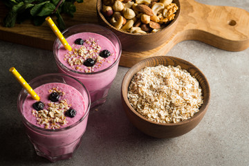 Glasses of berry smoothie with nuts, mint, blueberry, blackberry, raspberry, and yogurt on wooden table. Weight loss and diet concept. 