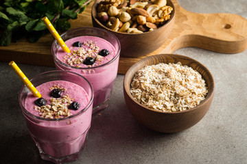 Glasses of berry smoothie with nuts, mint, blueberry, blackberry, raspberry, and yogurt on wooden table. Weight loss and diet concept. 