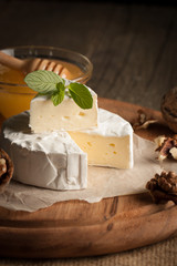 Camembert and brie cheese on wooden background with tomatoes, letuce and garlic. Italian food. Dairy products.