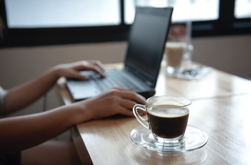 Coffee cup on the front desk with people  using laptop.