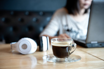 Coffee cup on the front desk with people  using laptop.